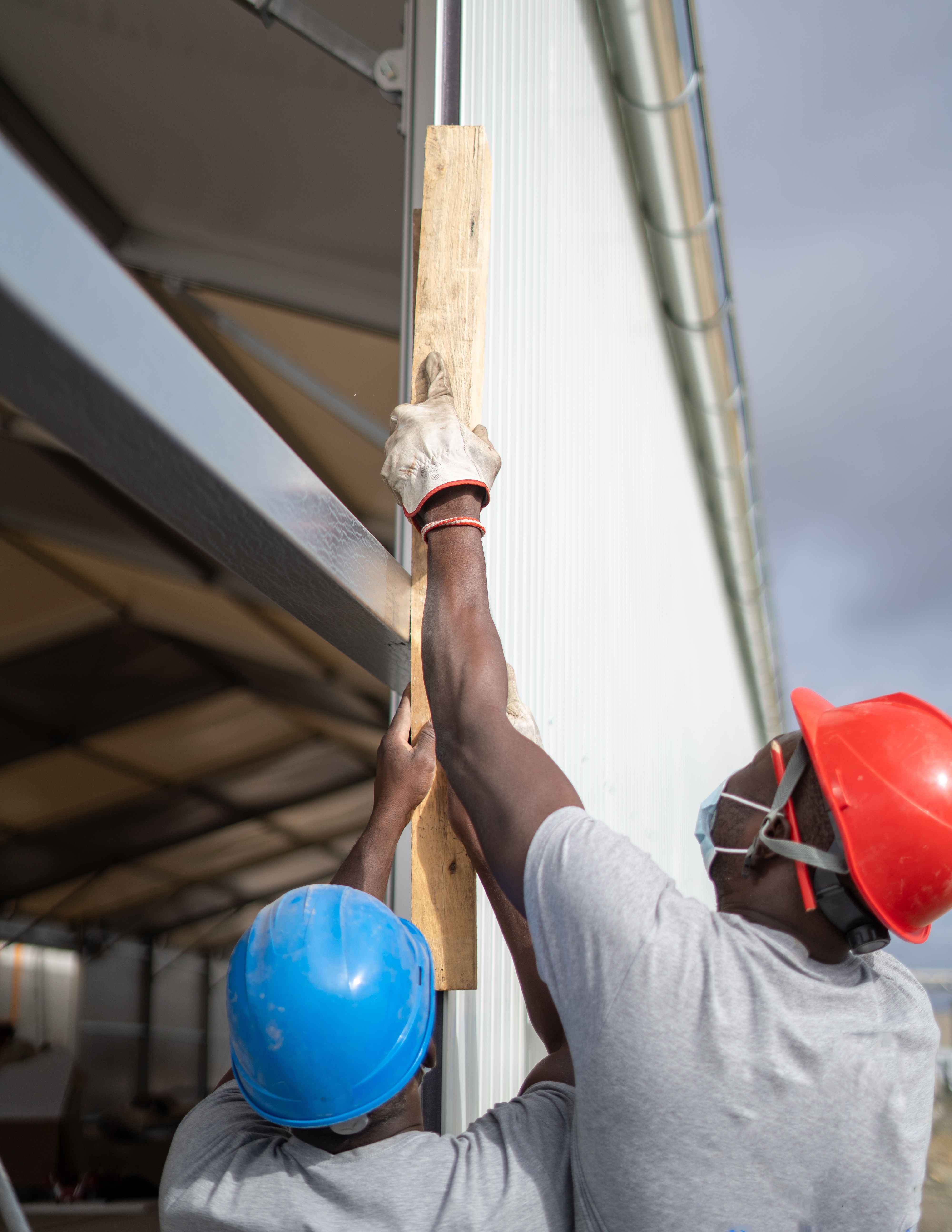 African American construction workers measuring and working on a wall